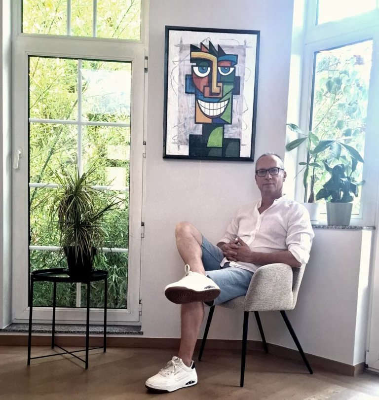 Ward Reekmans zittend voor zelf gemaakt schilderij